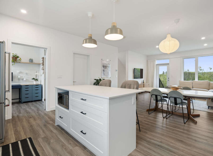 Discover modern living in this open-concept space, featuring a sleek kitchen island with integrated microwave and ample storage.