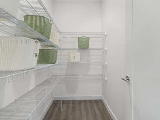 Discover ample storage in this spacious walk-in closet, featuring multiple wire shelves perfect for organizing your belongings.