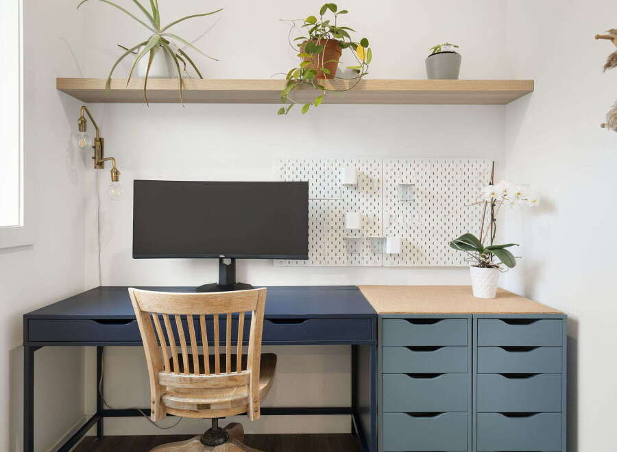 This home office features a modern desk setup with a sleek dark blue desk and a complementary grey drawer unit.