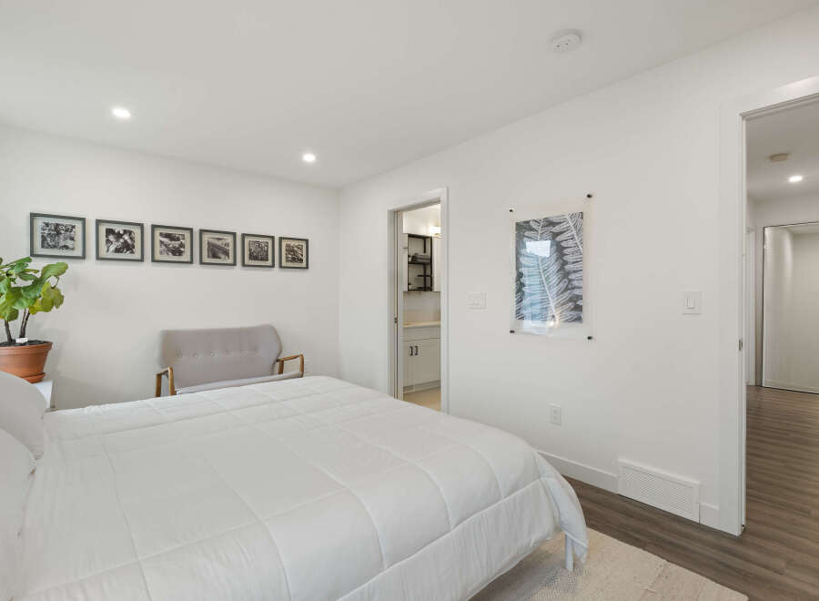 This bright and airy bedroom features a comfortable queen-size bed with crisp white linens, perfect for relaxation.