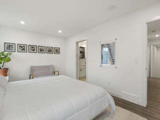 This bright and airy bedroom features a comfortable queen-size bed with crisp white linens, perfect for relaxation.
