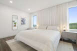 Experience serene comfort in this bright and airy bedroom, featuring a plush white duvet and a minimalist white metal bed frame.