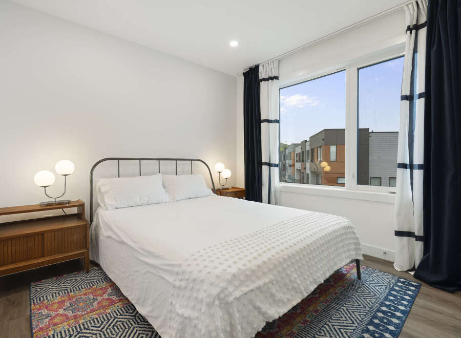 Experience modern comfort in this stylish bedroom, featuring a queen-sized bed with crisp white linens and a textured duvet.