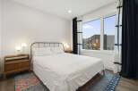 Experience modern comfort in this stylish bedroom, featuring a queen-sized bed with crisp white linens and a textured duvet.