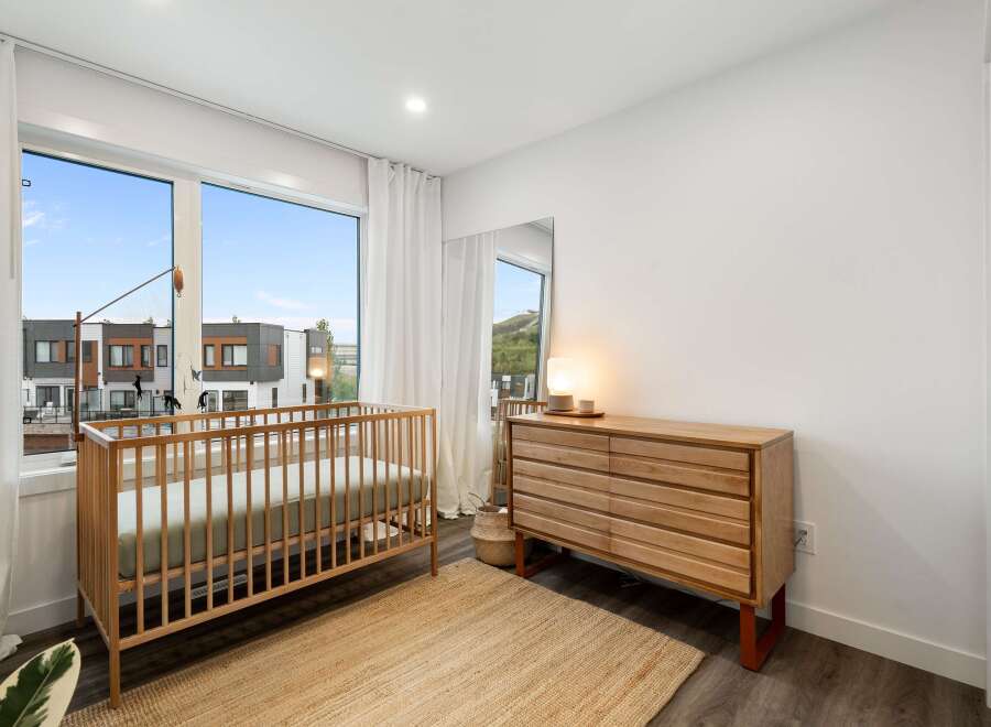 This charming nursery features a light wood crib and a matching dresser, creating a warm and inviting atmosphere.