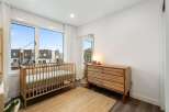 This charming nursery features a light wood crib and a matching dresser, creating a warm and inviting atmosphere.