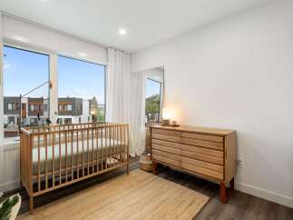 This charming nursery features a light wood crib and a matching dresser, creating a warm and inviting atmosphere.