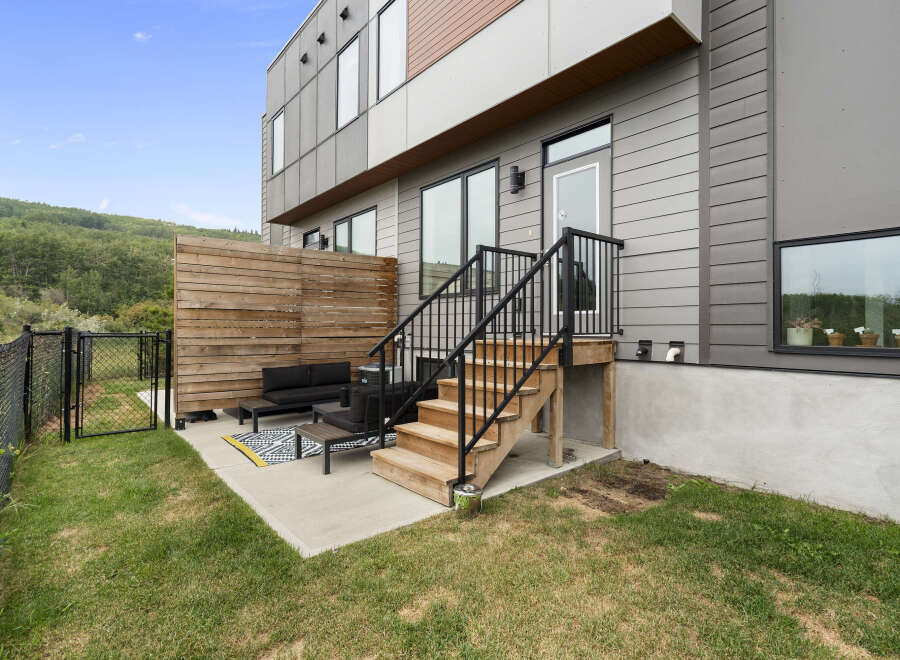 Enjoy outdoor living in this modern townhouse featuring a private patio with comfortable seating and a wooden privacy screen.