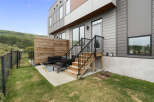 Enjoy outdoor living in this modern townhouse featuring a private patio with comfortable seating and a wooden privacy screen.