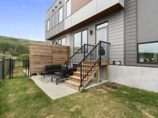 Enjoy outdoor living in this modern townhouse featuring a private patio with comfortable seating and a wooden privacy screen.