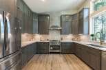 Experience modern luxury in this stunning kitchen, featuring sleek, dark gray cabinetry complemented by a classic white subway tile backsplash.