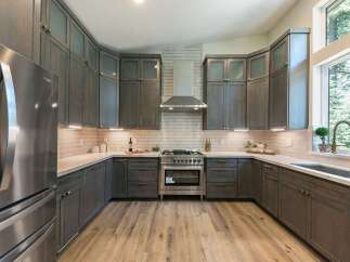 Experience modern luxury in this stunning kitchen, featuring sleek, dark gray cabinetry complemented by a classic white subway tile backsplash.