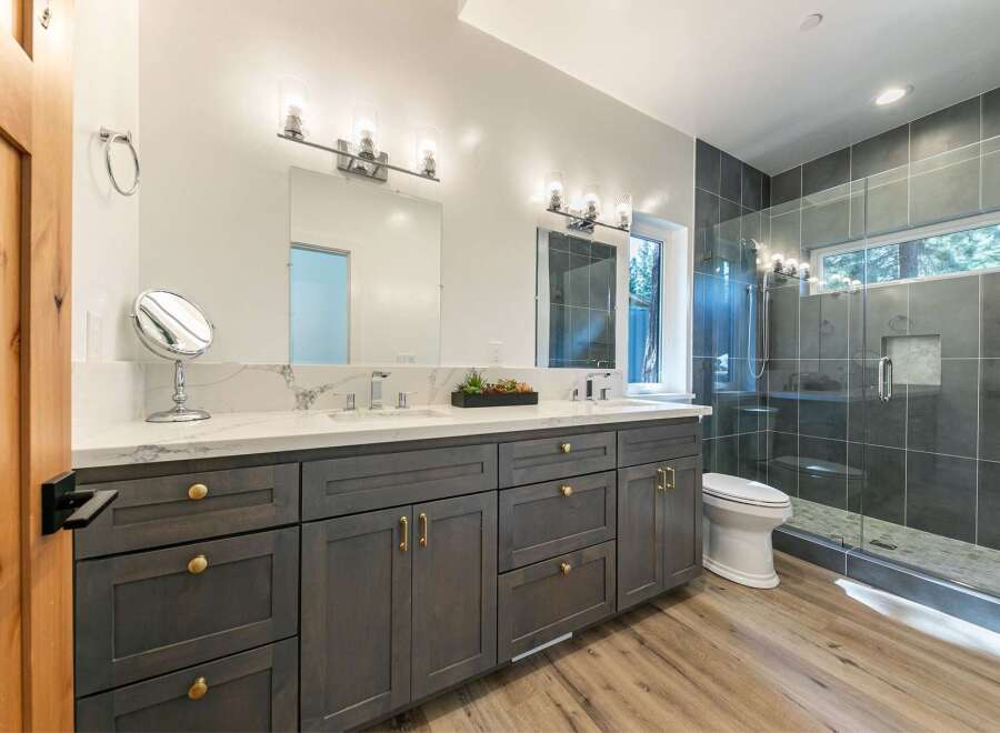 Experience modern luxury in this stunning bathroom featuring a spacious double vanity with elegant marble countertops and gold hardware.