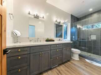 Experience modern luxury in this stunning bathroom featuring a spacious double vanity with elegant marble countertops and gold hardware.