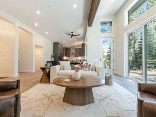 Experience modern living in this spacious great room, featuring soaring vaulted ceilings and a dramatic wooden beam.