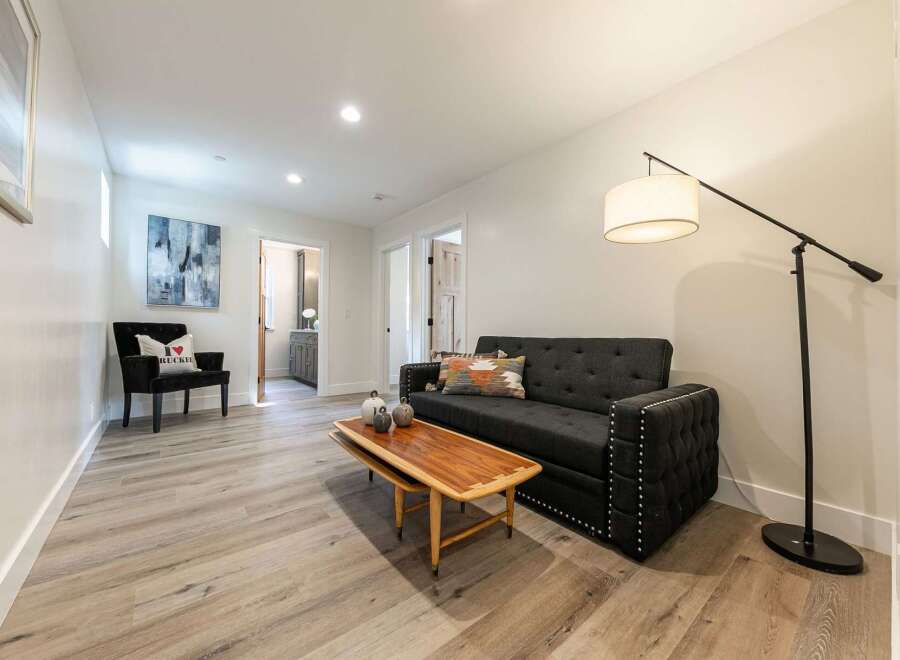Discover this inviting living space featuring a stylish dark gray tufted sofa adorned with decorative pillows and a unique wooden coffee table.