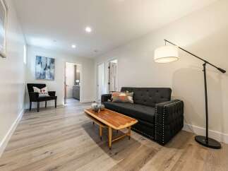 Discover this inviting living space featuring a stylish dark gray tufted sofa adorned with decorative pillows and a unique wooden coffee table.