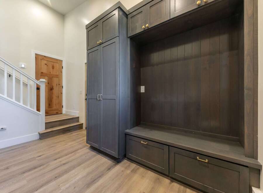 This entryway features a custom dark wood built-in with ample storage, including drawers and cabinets, perfect for organizing shoes and accessories.