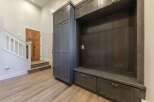 This entryway features a custom dark wood built-in with ample storage, including drawers and cabinets, perfect for organizing shoes and accessories.