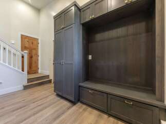 This entryway features a custom dark wood built-in with ample storage, including drawers and cabinets, perfect for organizing shoes and accessories.