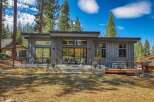 Experience modern mountain living in this stunning contemporary home, featuring sleek vertical siding and expansive windows that invite the natural beauty of the surrounding pine forest indoors.