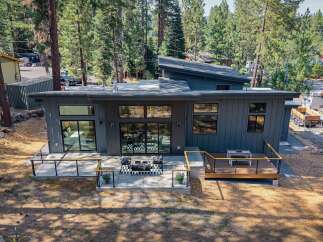 Experience modern living in this stunning contemporary home, featuring sleek dark siding and a unique asymmetrical roofline.