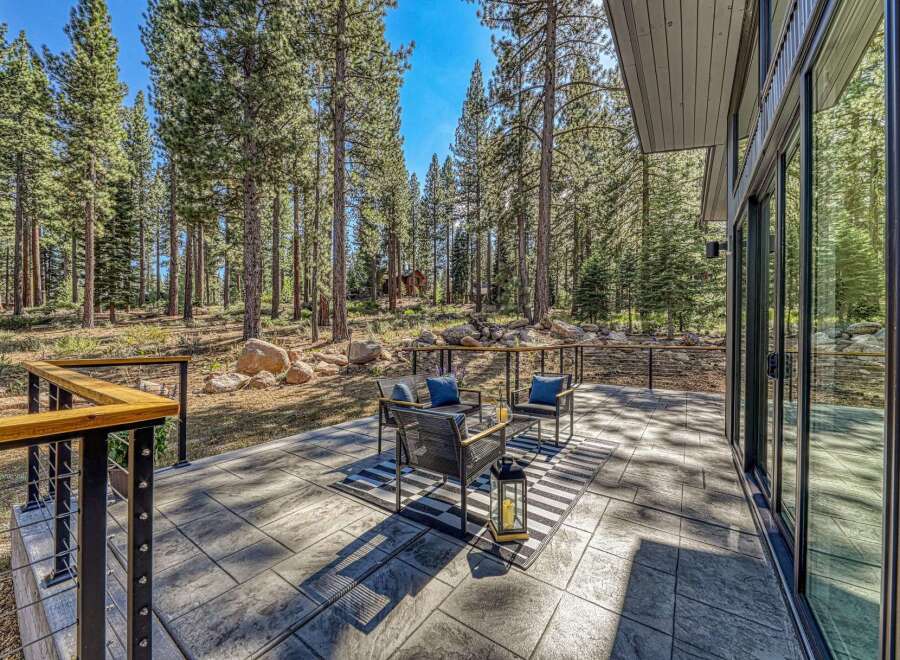 Experience seamless indoor-outdoor living with this stunning patio, nestled amongst towering pine trees.