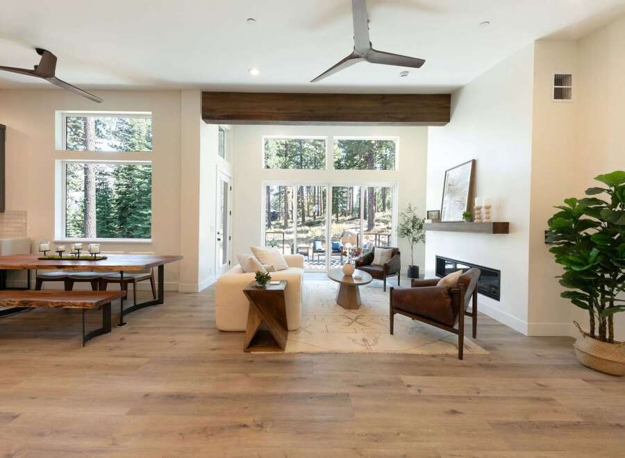 Experience modern living in this stunning open-concept great room, featuring soaring ceilings and a wall of windows that frame breathtaking forest views.
