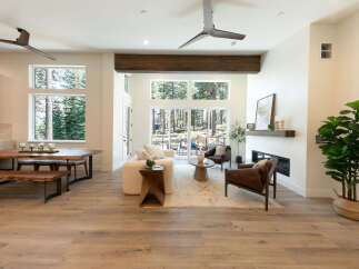 Experience modern living in this stunning open-concept great room, featuring soaring ceilings and a wall of windows that frame breathtaking forest views.