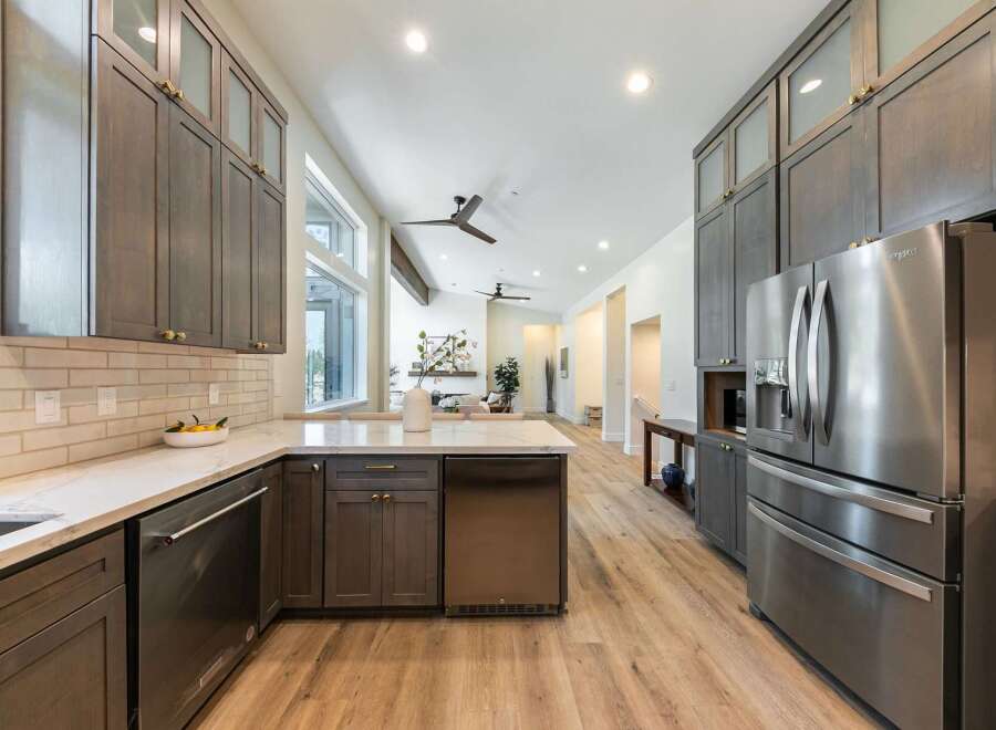 Experience luxury in this modern kitchen featuring sleek, dark wood cabinetry and a spacious island with a marble countertop.