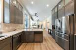 Experience luxury in this modern kitchen featuring sleek, dark wood cabinetry and a spacious island with a marble countertop.