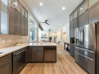 Experience luxury in this modern kitchen featuring sleek, dark wood cabinetry and a spacious island with a marble countertop.