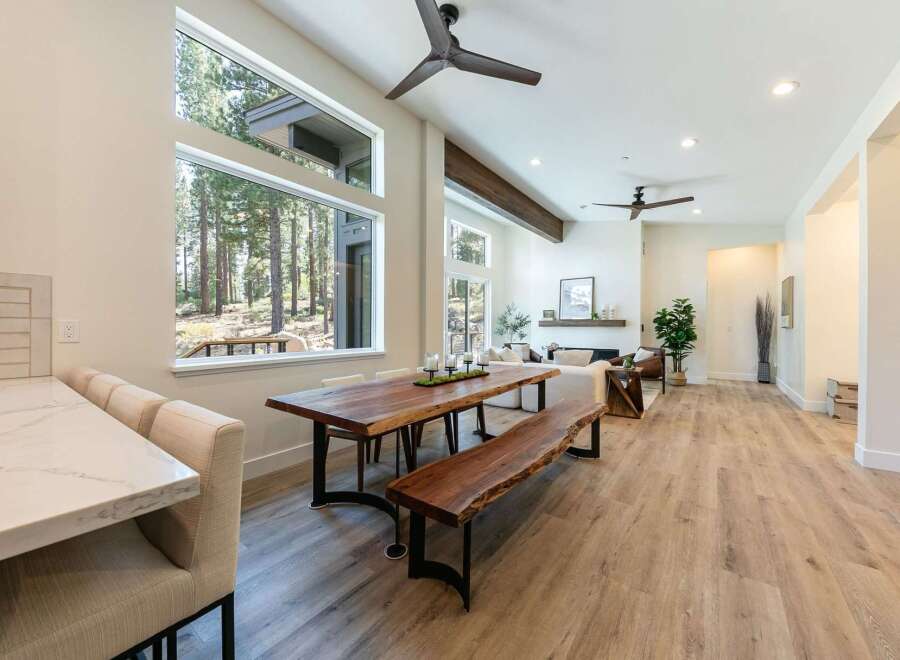 Experience modern living in this stunning open-concept home, featuring a spacious dining area with a live-edge wood table and bench, perfect for gatherings.