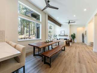 Experience modern living in this stunning open-concept home, featuring a spacious dining area with a live-edge wood table and bench, perfect for gatherings.