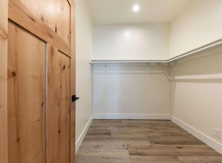 Step into this spacious walk-in closet, featuring a convenient built-in shelving system perfect for organizing your wardrobe.