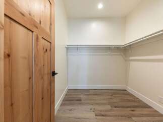 Step into this spacious walk-in closet, featuring a convenient built-in shelving system perfect for organizing your wardrobe.