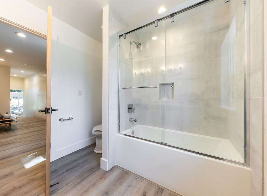 Step into a modern bathroom featuring a sleek bathtub with a glass enclosure and a rainfall showerhead.