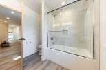 Step into a modern bathroom featuring a sleek bathtub with a glass enclosure and a rainfall showerhead.