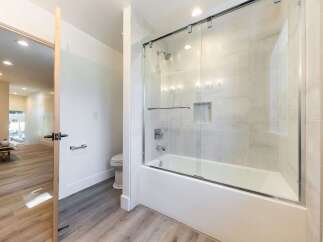 Step into a modern bathroom featuring a sleek bathtub with a glass enclosure and a rainfall showerhead.