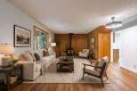Experience cozy living in this inviting living room, featuring a striking wood-paneled accent wall and a modern wood-burning stove.