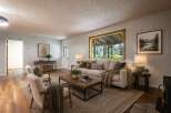 Step into this inviting living room, bathed in natural light from a large picture window overlooking lush greenery.