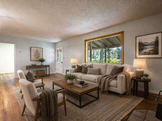 Step into this inviting living room, bathed in natural light from a large picture window overlooking lush greenery.