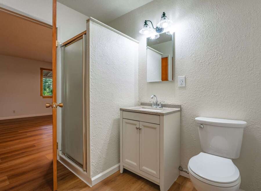 This bathroom features a modern vanity with a granite countertop and a sleek faucet, complemented by a textured white wall.