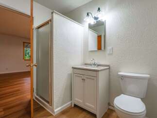 This bathroom features a modern vanity with a granite countertop and a sleek faucet, complemented by a textured white wall.