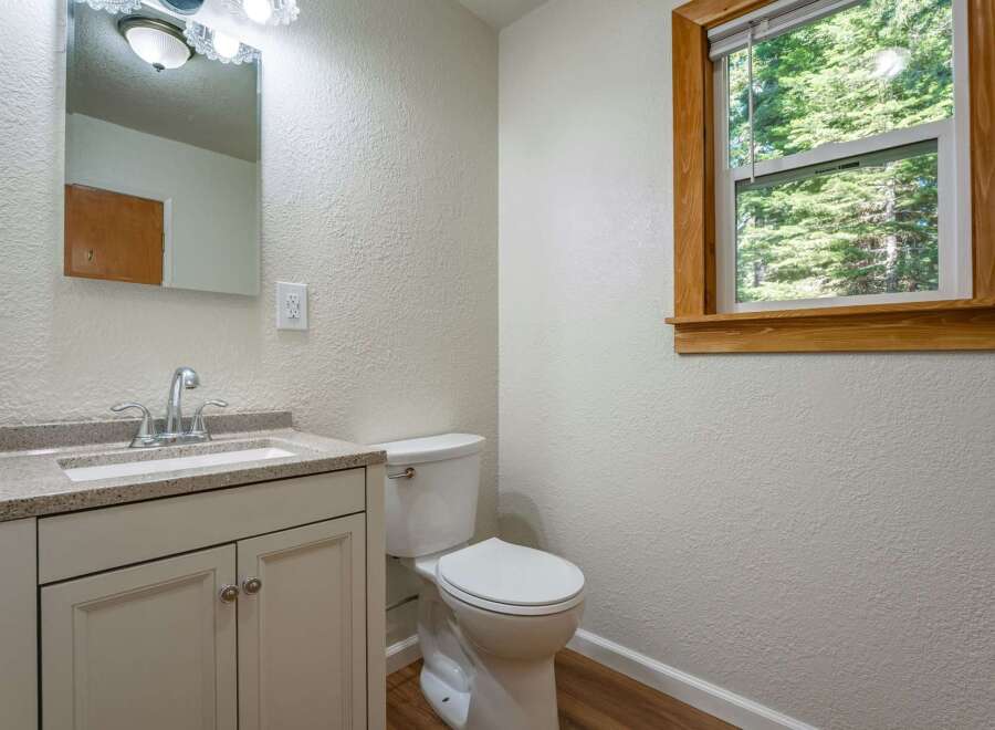 This charming bathroom features a modern vanity with a granite countertop and a sleek chrome faucet, complemented by a white toilet.
