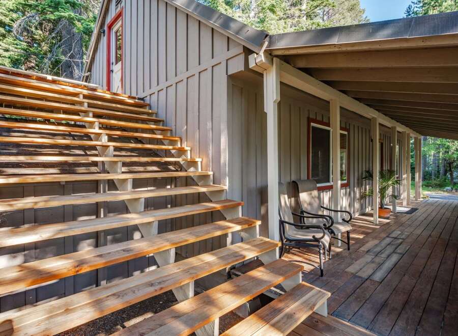 Ascend to this charming cabin retreat via a sturdy wooden staircase, leading to a welcoming covered porch perfect for enjoying the surrounding nature.