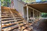 Ascend to this charming cabin retreat via a sturdy wooden staircase, leading to a welcoming covered porch perfect for enjoying the surrounding nature.