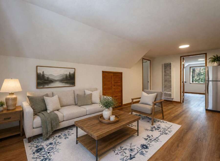 Discover comfortable living in this charming living space, featuring a plush sofa adorned with decorative pillows and a cozy throw blanket.
