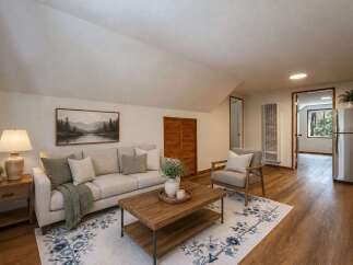 Discover comfortable living in this charming living space, featuring a plush sofa adorned with decorative pillows and a cozy throw blanket.