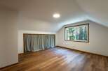 Discover this charming attic room, featuring a large window that floods the space with natural light and offers serene forest views.